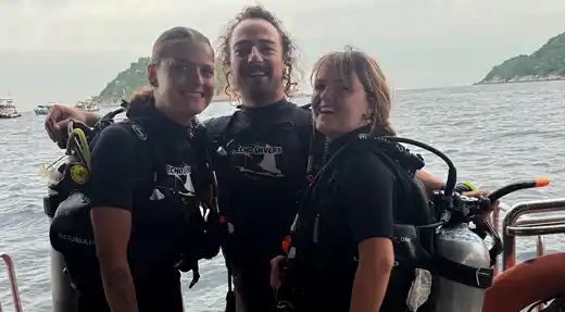 Three smiling fun divers wearing scuba gear on the Echo Divers boat in Koh Tao before a dive.