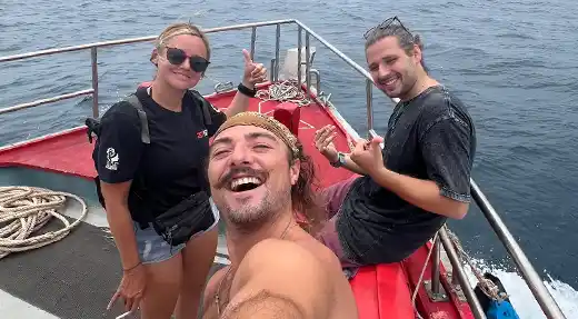 Three smiling fun divers wearing scuba gear on the Echo Divers boat in Koh Tao before a dive.