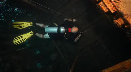 Scuba diver following a guideline while penetrating a shipwreck during advanced wreck training in Koh Tao, Thailand