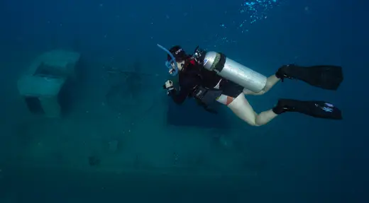Scuba diver approaching a shipwreck while maintaining trim and distance during advanced wreck training in Koh Tao, Thailand
