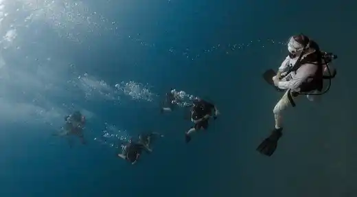  A group of fun divers descending together in clear blue water, photographed during an Echo Divers Koh Tao dive trip. 