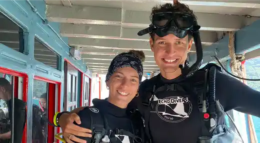 Two smiling SSI Basic Diver students on the Echo Divers Koh Tao dive boat before their training session.